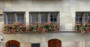 Bicycles parked against a European-style building adorned with vibrant flowers, creating a picturesque city street view.